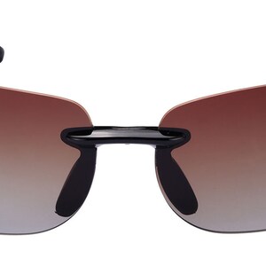 May include: Black sunglasses with a brown gradient lens. The sunglasses have a rimless design and a sleek, modern look.