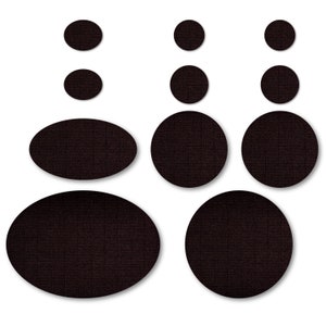 May include: A set of nine black fabric circles and ovals of varying sizes. The circles and ovals are arranged in a symmetrical pattern.