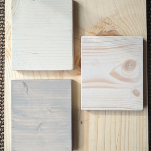 May include: Three wood samples, one is a light natural wood, one is a light gray wood, and one is a white wood.