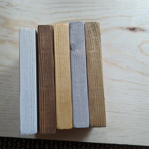 May include: Five wooden boards, each painted a different color. The boards are arranged vertically from left to right: white, brown, yellow, gray, and brown.