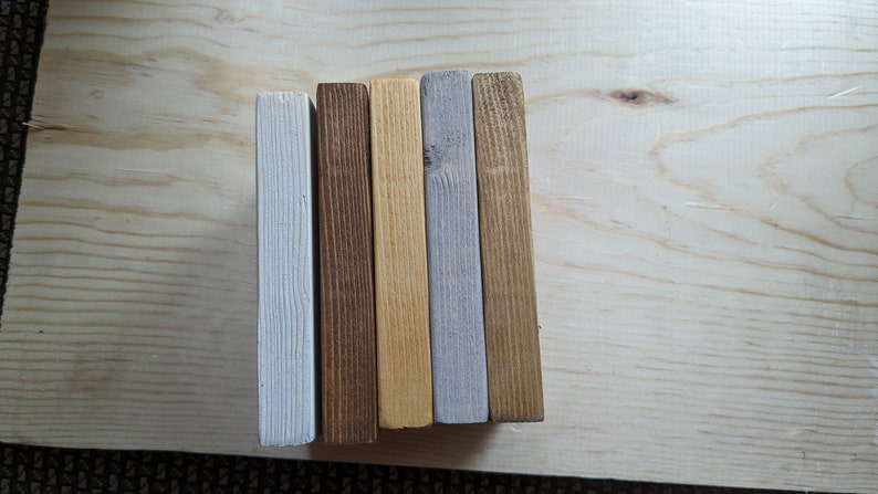 May include: Five wooden boards, each painted a different color. The boards are arranged vertically from left to right: white, brown, yellow, gray, and brown.