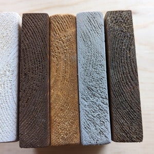 May include: Five wooden boards, each painted a different color: white, dark brown, light brown, light blue, and dark gray.