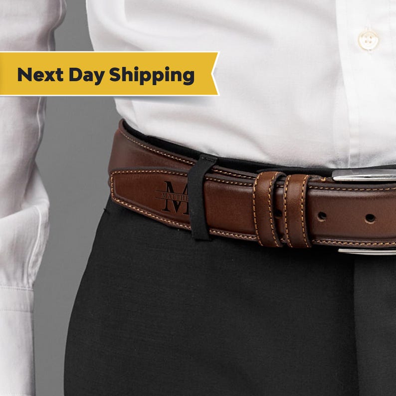 May include: A brown leather belt with a personalized engraved metal buckle. The buckle has the letter "M" and the word "Matthew" engraved on it.