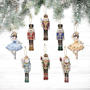 May include: A collection of wooden Christmas ornaments featuring nutcrackers, a ballerina, and a mouse king. The ornaments are painted in vibrant colors, including red, blue, and gold, and are suspended by gold strings.