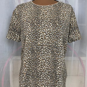 May include: A short-sleeved, white t-shirt with a brown and black leopard print.