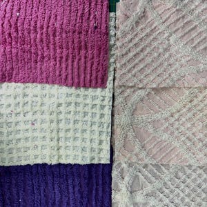 May include: Close-up of colorful fabric swatches. The swatches include textured pink, white, and purple sections. The fabric on the right side is a light pink with a diamond pattern.