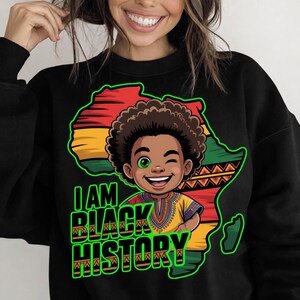 Peut inclure: Sweat-shirt noir avec une illustration de dessin anim&eacute; d'un enfant noir souriant, faisant un clin d'&oelig;il, sur fond de carte de l'Afrique en rouge, jaune et vert. Les mots "I AM BLACK HISTORY" sont &eacute;crits en vert.
