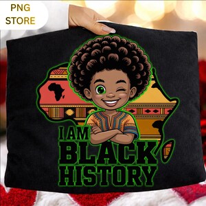 Peut inclure: Coussin noir avec un graphisme color&eacute; d'un enfant souriant avec une afro, sur fond de carte de l'Afrique. Le texte "I AM BLACK HISTORY" est affich&eacute; en vert et noir.
