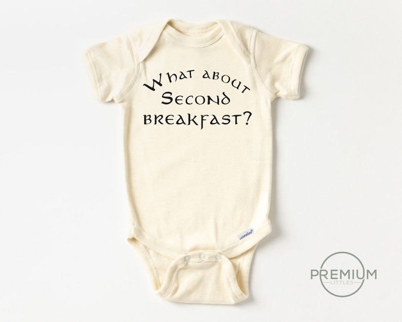 May include: A cream-coloured baby onesie with short sleeves and black text that reads "What about second breakfast?"