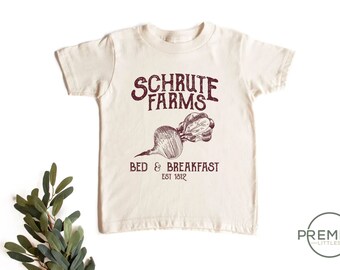 May include: A beige toddler t-shirt with a maroon graphic of a beet and the text "Schrute Farms Bed & Breakfast Est 1812".