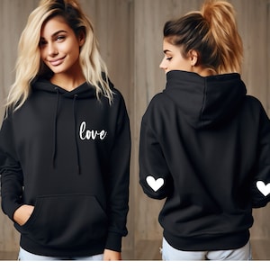 May include: Black hooded sweatshirt with the word "love" printed on the front and white heart designs on the sleeves.