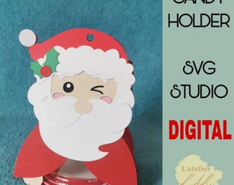 May include: A red and white Santa Claus candy holder with a winking face, holly accents, and the text "CANDY HOLDER" and "DIGITAL". The holder is designed with a round base and a red and white striped pattern.