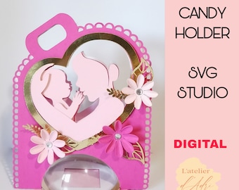 May include: Pink and gold candy holder with a cutout design of a mother and child. The holder has a heart-shaped opening and a clear plastic window for displaying candy. The text "CANDY HOLDER" and "SVG STUDIO" is visible in the image.