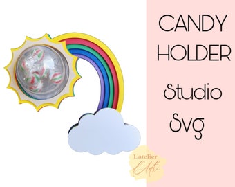 May include: A wooden rainbow candy holder with a sun and a cloud. The sun has a clear dome to hold candy. The rainbow is made of five colors: red, orange, yellow, green, and blue. The text "CANDY HOLDER Studio Svg" is written in black on a pink background.
