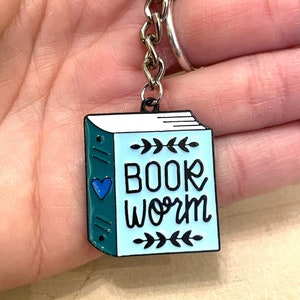 May include: A blue and green enamel book charm keyring with the text "BOOK WORM" and a small blue heart.