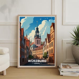 May include: A framed art print of Würzburg, Germany, featuring a detailed illustration of a European city street with colorful buildings and a tall clock tower under a blue sky. The print includes the city's name.