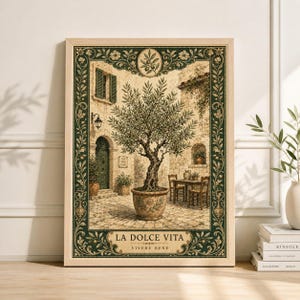 May include: A framed art print showing an Italian courtyard. It features an olive tree in a pot, a stone building, and the text "LA DOLCE VITA" and "VIVERE BENE". The frame is light wood with a dark green border, evoking a sense of rustic charm.
