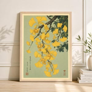 May include: A framed print depicting a ginkgo tree branch with vibrant yellow leaves and small, round fruits. The artwork has a pale green background and includes Japanese text.
