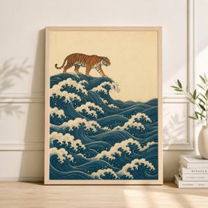 May include: Framed art print featuring a tiger walking atop stylized ocean waves. The tiger is orange and black, set against a cream-colored background. The waves are depicted in shades of blue and white, creating a dynamic and artistic composition.