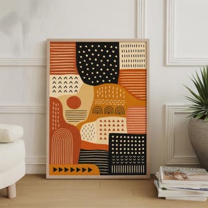 May include: Abstract art print in a wooden frame. The artwork features a collage of geometric shapes and patterns in shades of orange, black, beige, and brown. The design includes dots, lines, triangles, and arches, creating a modern and stylish aesthetic.