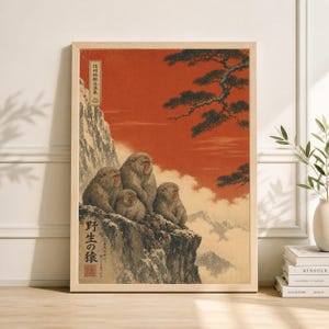 May include: A framed print featuring a traditional Japanese woodblock print style. The artwork depicts a group of snow monkeys perched on a cliffside, with a red sky and mountain range in the background. Japanese text is visible.