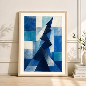 May include: Abstract art print featuring a geometric design in shades of blue and white. The artwork is framed in a light wood frame and depicts a stylized mountain or tree shape against a checkered background. The print is displayed indoors.