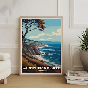 May include: Framed art print featuring a coastal landscape with the text "Carpinteria Bluffs - California." The artwork depicts a tree, cliffs, ocean, and sky in shades of blue, brown, and green. The print is in a light wood frame.