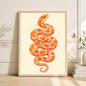 May include: A framed print showing a detailed illustration of a snake. The snake is in shades of orange, yellow, and pink, with a patterned design. The artwork is set against a cream background, and framed in light wood.