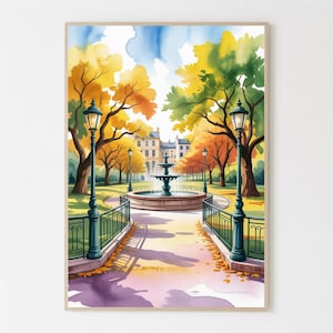 May include: Watercolor painting of a park scene with a fountain, trees, and lampposts. The trees display autumn colors of yellow, orange, and green. A pathway leads to the fountain, with a building in the background. The artwork is framed.