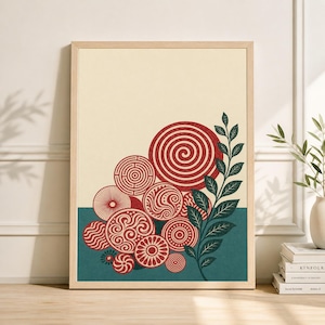 Op de afbeelding: Een ingelijste kunstdruk met een verzameling rode en crèmekleurige cirkelvormige ontwerpen met verschillende patronen. Het kunstwerk bevat een blauwgroene band aan de onderkant en een takje groene bladeren. De achtergrond is crèmekleurig.