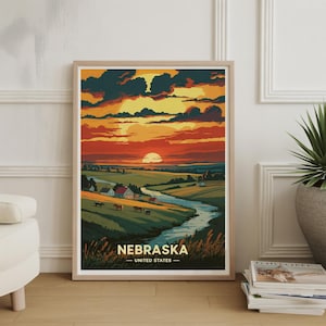 May include: Framed art print featuring a stylized landscape of Nebraska at sunset. The artwork depicts a river winding through green fields, with houses and horses. The sky is filled with orange and dark clouds, and the text "NEBRASKA - UNITED STATES" is at the bottom.