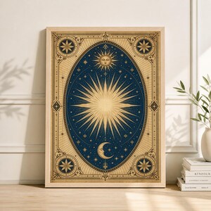 May include: A framed celestial art print featuring a sunburst design in gold against a dark blue background. The artwork includes a crescent moon, stars, and decorative border elements. The print is in a light wood frame.