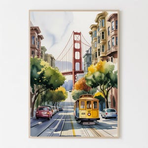 May include: Watercolor print of a San Francisco street scene featuring a yellow cable car, the Golden Gate Bridge, and colorful buildings. The artwork captures the city's iconic landmarks with a vibrant, artistic style. Cars line the street, and trees add a touch of nature.