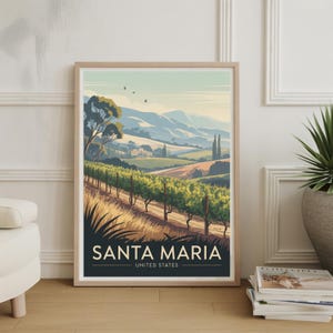 May include: A framed art print featuring a landscape of Santa Maria, United States. The artwork depicts a vineyard with rows of grapevines, rolling hills, and a clear sky. The print has a light wood frame and the text "SANTA MARIA" is displayed.