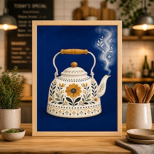 Op de afbeelding: Een ingelijste print van een decoratieve theepot met een bloemenontwerp in geel, zwart en groen op een crèmekleurige achtergrond. De theepot heeft een houten handvat en een tuit met stoom die eruit komt tegen een donkerblauwe achtergrond.