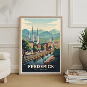 May include: A framed art print featuring a stylized illustration of Frederick, Maryland. The artwork depicts a canal, buildings, and church steeples against a backdrop of rolling hills and a blue sky. The text "FREDERICK UNITED STATES" is at the bottom.