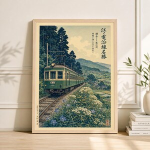 Könnte beinhalten: Gerahmter Druck eines japanischen Landschaftsbildes mit einem grünen Zug auf Gleisen. Das Kunstwerk enthält japanischen Text und zeigt eine ruhige Aussicht mit Bäumen, Blumen und Bergen. Der Rahmen ist aus Holz.
