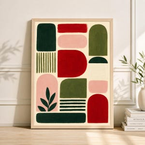 May include: Abstract art print in a wooden frame. The artwork features geometric shapes in shades of red, green, pink, and white on a cream background. The design includes rectangles, arches, and a leaf motif, creating a modern aesthetic.