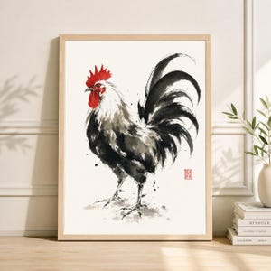 Puede incluir: Pintura a la acuarela de un gallo enmarcada. El gallo está representado en tonos negros, blancos y grises, con una cresta y barbillas rojas vibrantes. La obra de arte tiene un estilo minimalista, con pinceladas de tinta y un toque de influencia japonesa.