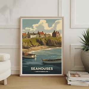 Puede incluir: Una impresión artística enmarcada que presenta una escena costera con el texto "SEAHOUES - NORTHUMBERLAND". La obra de arte representa casas con tejados rojos en un acantilado, barcos en el agua y una playa de arena. El cielo es azul con nubes blancas.