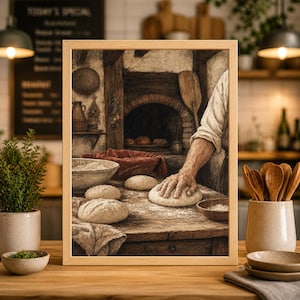 May include: Framed print of a vintage bakery scene. A baker's hands knead dough on a wooden table dusted with flour. A brick oven and bowls of flour are in the background. The print is in a wooden frame.