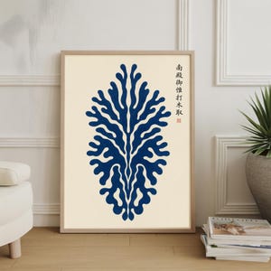 May include: A framed art print with a navy blue abstract design, similar to a tree or coral, set against a cream backdrop. Japanese text is visible in the top right corner. The print is displayed on a wooden floor.