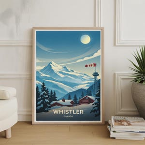 May include: A framed art print featuring a winter landscape with snow-covered mountains, evergreen trees, and a full moon. The print includes a tower with a windsock and the text "WHISTLER CANADA" in white letters.