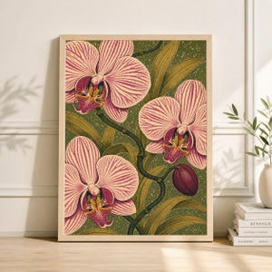 Puede incluir: Una impresión botánica enmarcada con orquídeas rosas con pétalos rayados y centros amarillos y rojos. Las orquídeas se colocan sobre un fondo verde moteado con hojas y tallos verdes. La obra de arte está en un marco de madera clara.