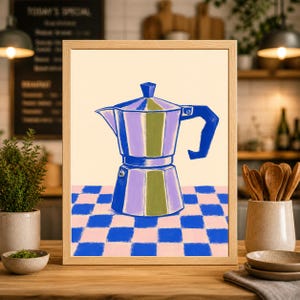 May include: A framed print featuring a stylized illustration of a blue and purple stovetop espresso maker. The artwork is set against a cream background and a checkered blue and pink table. The print is in a wooden frame.
