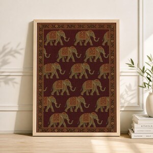 May include: Framed print featuring a repeating pattern of elephants with ornate saddle blankets. The elephants are in a row on a burgundy background with a decorative border. The frame is a light wood color.