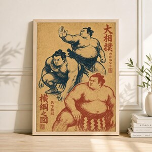 May include: A framed vintage-style print depicting three sumo wrestlers in dynamic poses. The artwork uses a muted colour palette with shades of brown, red, and blue. Japanese text is visible on the print.