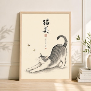 Puede incluir: Una impresión artística enmarcada con una ilustración en acuarela de un gato estirándose con pelaje gris y blanco. Dos abejas vuelan cerca del gato. La obra de arte incluye caracteres chinos y un sello rojo.
