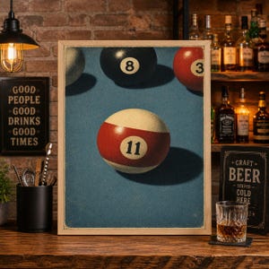 May include: A framed print featuring a close-up of several billiard balls on a blue surface. The focus is on the number 11 ball, with the number 8 and 3 balls visible. The print has a vintage aesthetic, with a wooden frame.