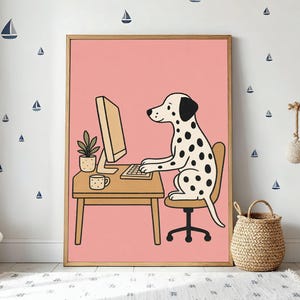 May include: A framed print featuring a Dalmatian dog sitting at a desk, working on a computer. The dog is black and white with a beige chair and desk. The background is pink, with a small plant and mug on the desk.
